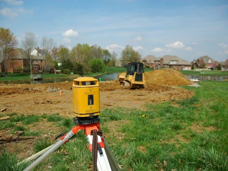 Survey equipment positioned on a redevelopment site to establish property boundaries before demolition, planning, and new construction activities.