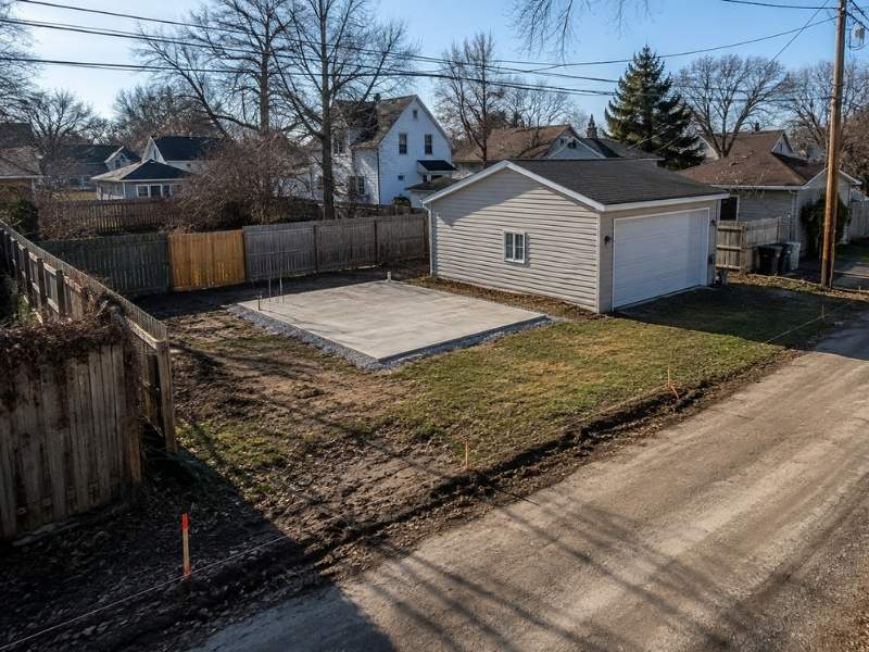 Land surveyor in Dayton, Ohio, measuring an old retaining wall near a property boundary to verify its position before repairs or construction.